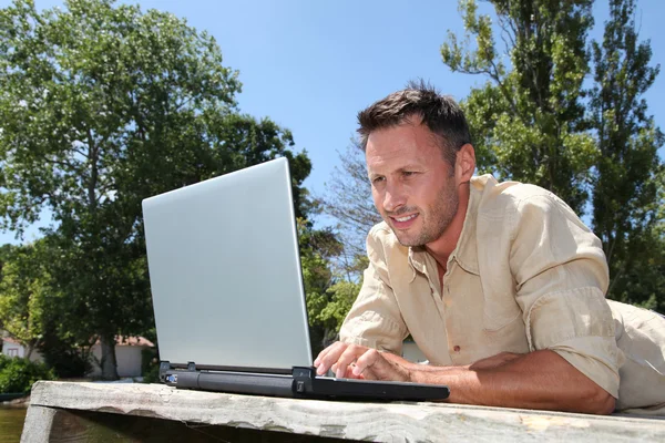 Man with laptop on a pontoon — Stock Photo, Image