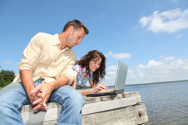 Koppel met laptop op een ponton — Stockfoto