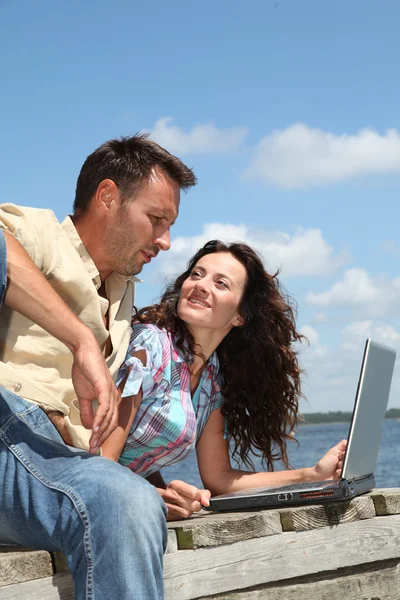 Couple with laptop on a pontoon — Stock Photo, Image
