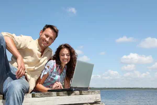 Couple with laptop on a pontoon — Stock Photo, Image