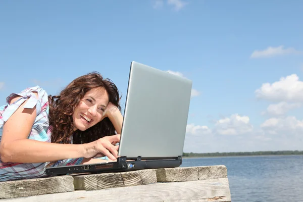 Woman with laptop on a pontoon — Stock Photo, Image