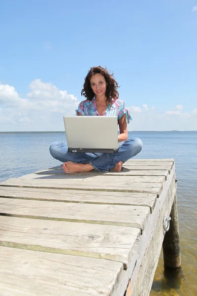 Жінка з ноутбуком на понтоні — стокове фото