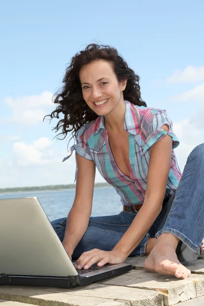 Kvinna med laptop på en ponton — Stockfoto