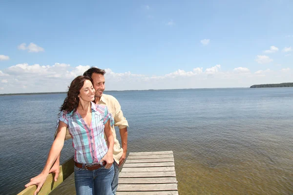 Casal amoroso em pé em um pontão perto de um lago — Fotografia de Stock