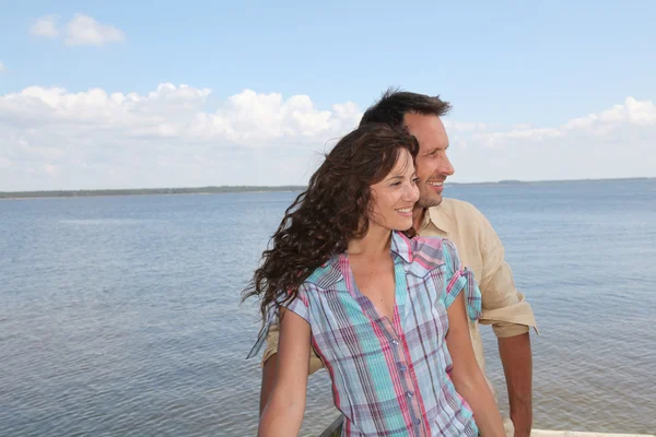Älskande par stående på en ponton vid en sjö — Stockfoto