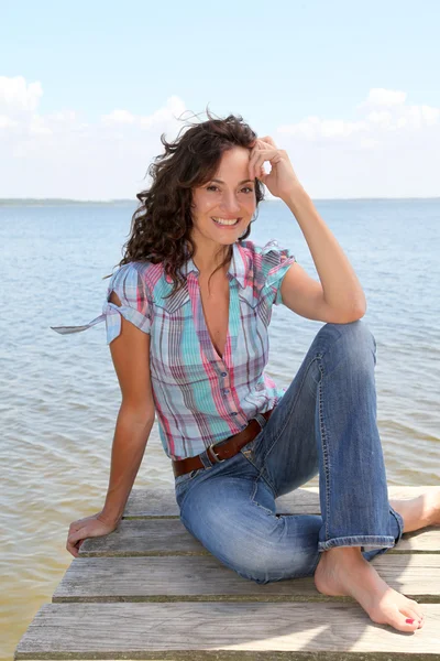 女子坐在湖边的浮桥 — 图库照片