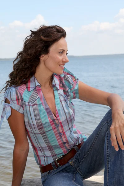 Donna seduta su un pontone vicino a un lago — Foto Stock