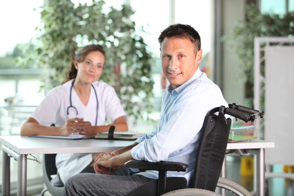 Man in wheelchair with doctor — Stock Photo, Image