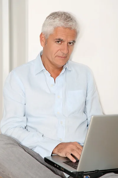 Senior man med bärbar dator Stockbild