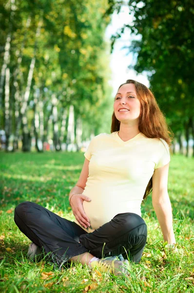 Krásná těhotná žena relaxuje v parku Stock Obrázky