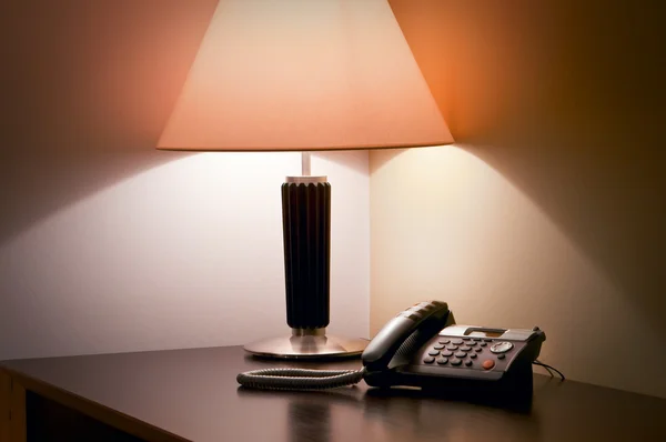 Стол с лампой и телефоном на нем — стоковое фото