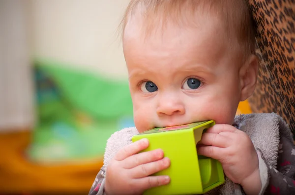 Baby håller en grön kloss inför kameran — Stockfoto