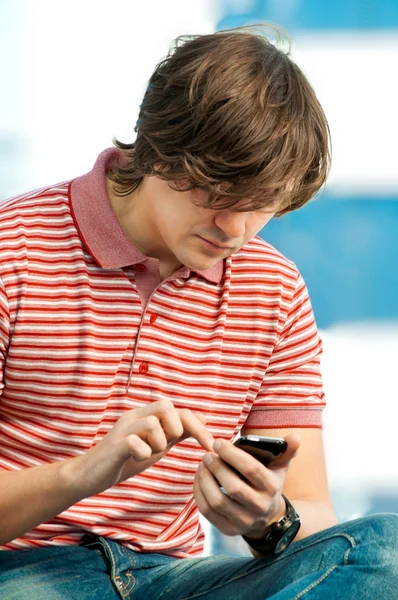 Retrato de un joven de moda escribiendo un mensaje en el teléfono móvil — Foto de Stock