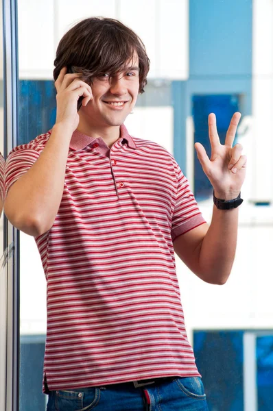 Улыбающийся молодой человек, говорящий по мобильному телефону - в помещении — стоковое фото