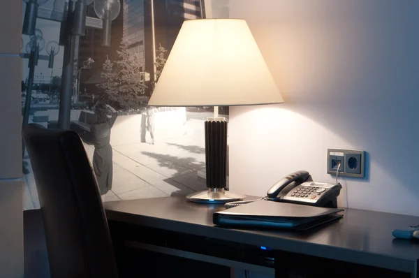 Este é um close-up de uma mesa com uma lâmpada e telefone sobre ele — Fotografia de Stock