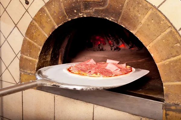Bakade pizza vid elden i ugnen — Stockfoto