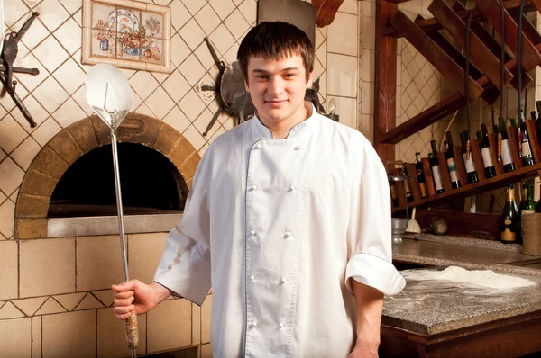 オーブンの隣に立っている若いシェフ — ストック写真
