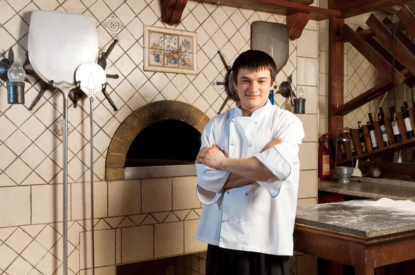 Молодой повар, стоящий рядом с духовкой — стоковое фото