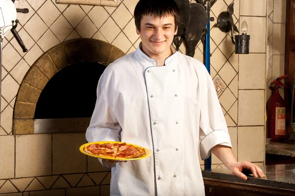 A young chef standing next to oven — Stockfoto