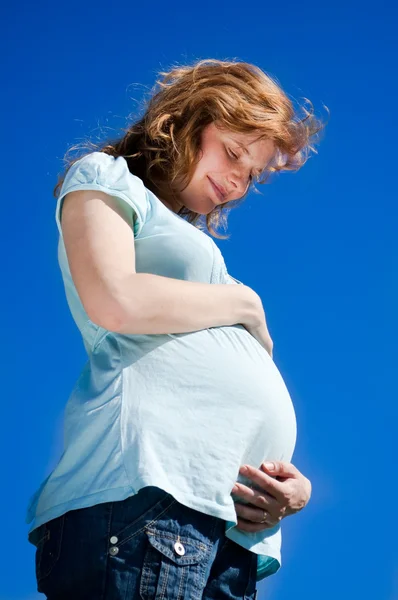 Krásná těhotná žena při pohledu na její břicho — Stock fotografie
