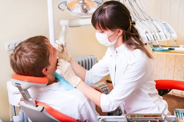 Jonge tandarts geeft een behandeling aan haar patiënt — Stockfoto