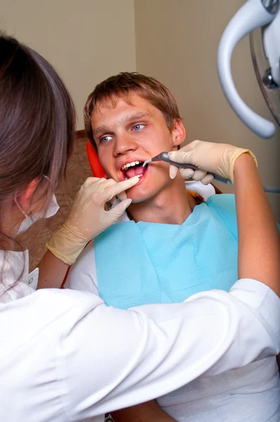 Dentista joven dando un tratamiento a su paciente —  Fotos de Stock