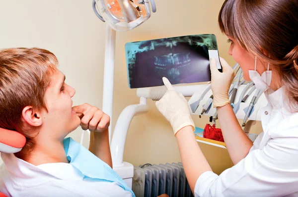 Стоматолог пояснює деталі рентгенівського знімка її пацієнта — стокове фото