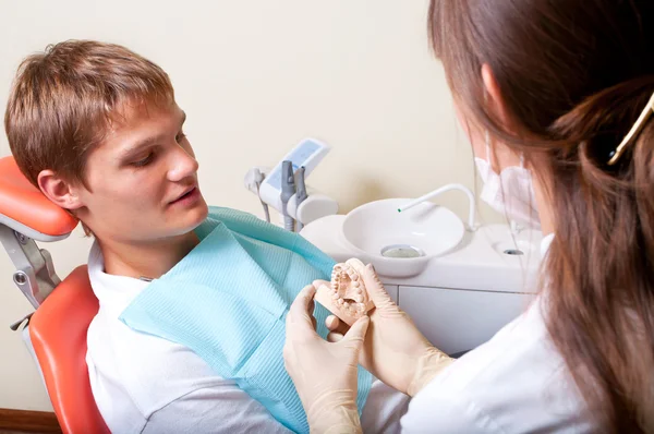 Стоматолог показывает стоматологические формы своему пациенту — стоковое фото