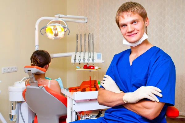 Молодой дантист в своем кабинете смотрит на зрителя — стоковое фото