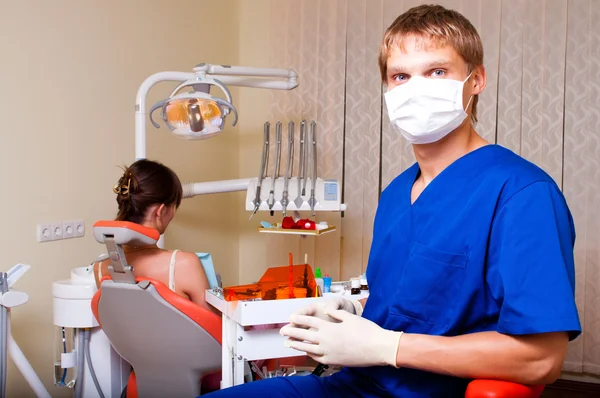 Молодой дантист в своем кабинете смотрит на зрителя — стоковое фото