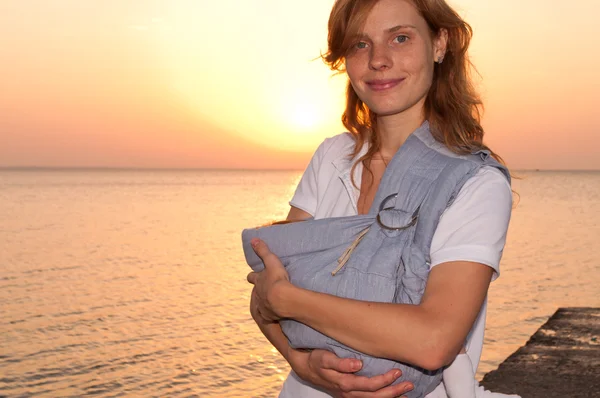 Jovem mãe com seu bebê na funda — Fotografia de Stock