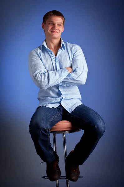 Młody mężczyzna siedzący bar krzesło z skrzyżowanymi rękami — Zdjęcie stockowe