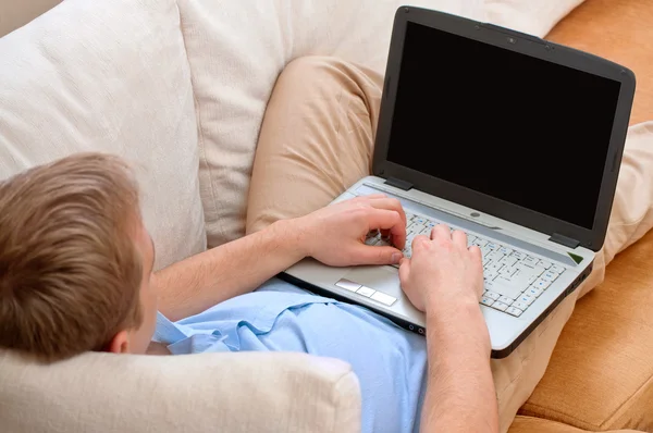 Νεαρός άνδρας, χρησιμοποιώντας ένα φορητό υπολογιστή στο σπίτι — Φωτογραφία Αρχείου