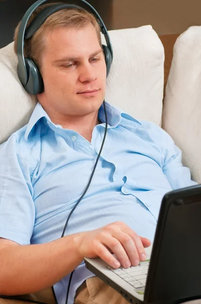 Περιστασιακή άνθρωπος ακούγοντας μουσική με ακουστικά στο σπίτι — Φωτογραφία Αρχείου