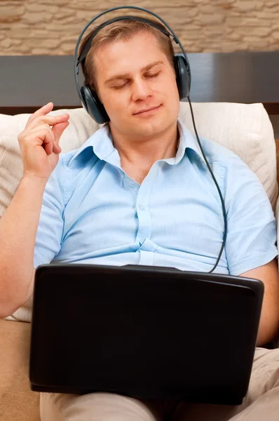 Homme décontracté écoutant de la musique avec écouteurs à la maison — Photo