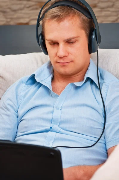 Hombre casual escuchando música con auriculares en casa — Foto de Stock