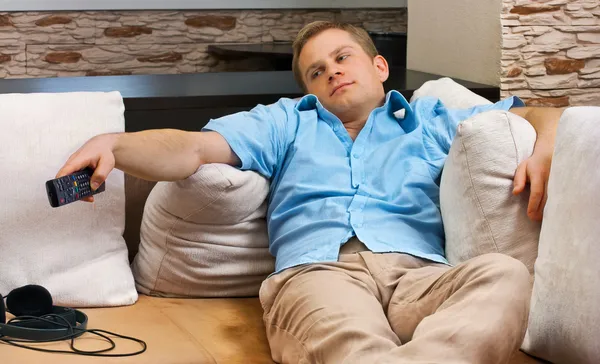 Мужчина лежит на диване и смотрит телевизор дома . — стоковое фото