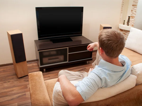 Mannen som ligger på soffan och tittar på TV hemma. — Stockfoto