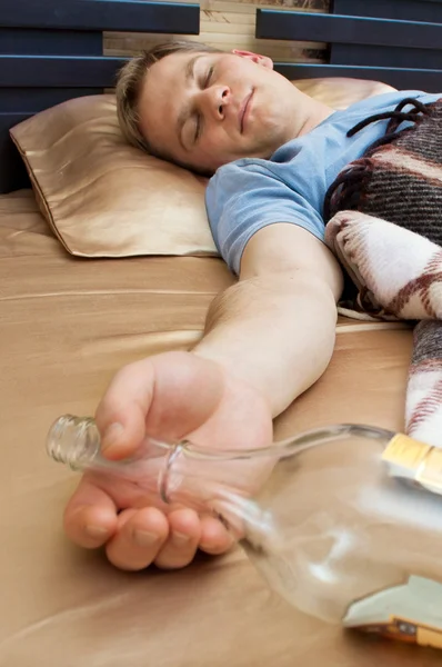 Wiskey bir şişe ile kanepede uyuyan genç bir adam — Stok fotoğraf