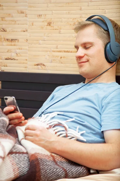 젊은 남자가 누워서 음악을 듣고 있다 — 스톡 사진