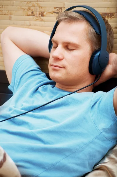 Couché jeune homme écoutant de la musique — Photo
