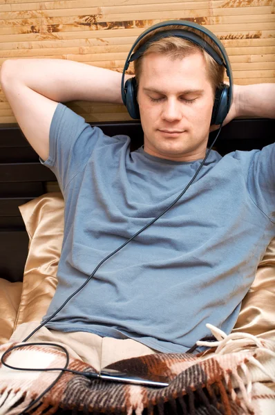 This is a photograph of laying young man listening music — Stock Photo, Image