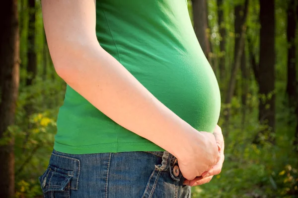 Nahaufnahme einer schwangeren Frau, die ihre Hände auf ihrem Bauch hält — Stockfoto