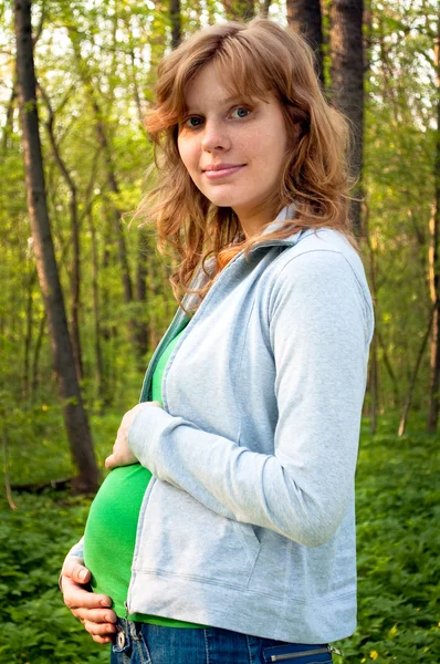 Feliz joven embarazada sosteniendo sus manos sobre su barriga —  Fotos de Stock