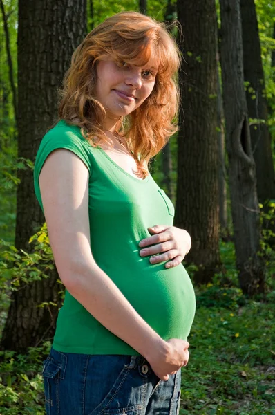 幸福着她的手在她的肚子上的年轻孕妇 — 图库照片