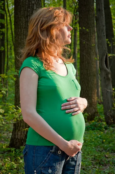 Šťastná mladá těhotná žena drží ruce na její bříško — Stock fotografie