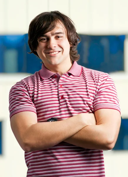 Portrait of a happy young man standing with folded hands Stock Photo