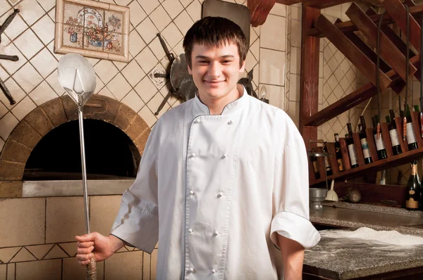 Ein junger Koch steht neben dem Ofen lizenzfreie Stockfotos
