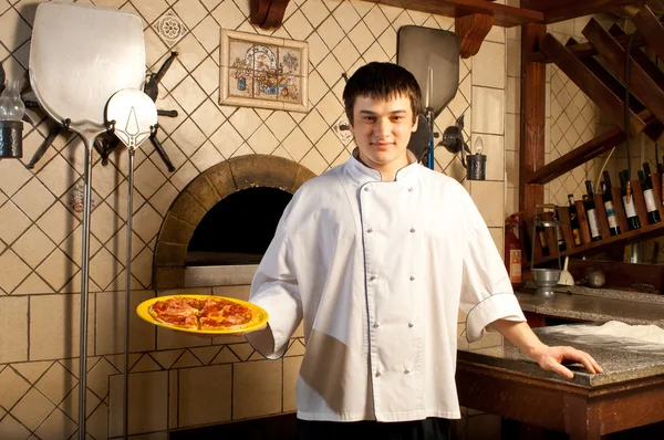 Молодой повар, стоящий рядом с духовкой Стоковая Картинка