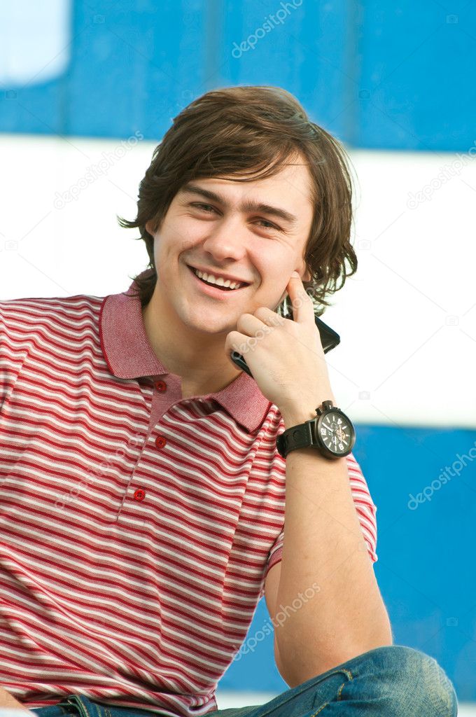 Happy young man with mobile phone, looking at camera